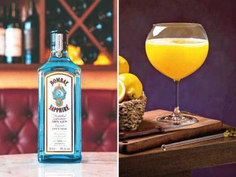 Side-by-side image of a Bombay Sapphire gin bottle and a glass of orange-hued Orange Blossom cocktail garnished with lemon