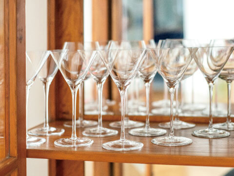 Rows of V-shaped cocktail glasses lined up on a wooden shelf, showing their signature stemmed martini glass shape