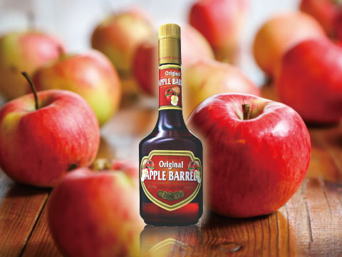 A bottle of Original Apple Barrel liqueur surrounded by fresh red apples on a wooden surface