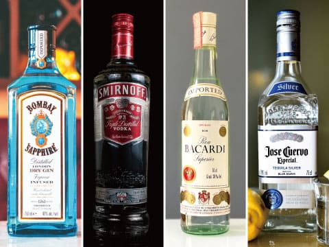 Four bottles of clear spirits—gin, vodka, rum, and tequila—stand side by side against a plain background.