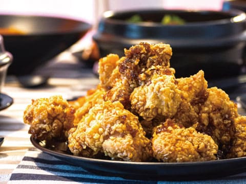 A plate of crispy Japanese fried chicken karaage glazed with sauce, served on a striped tablecloth