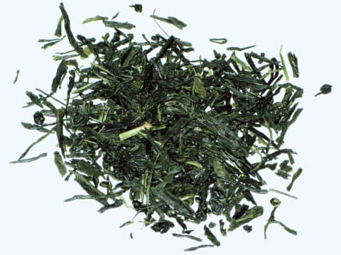 A pile of dark green, needle-like gyokuro tea leaves on a white background.