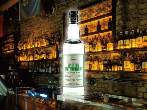 Bottle of Spirytus Rektyfikowany rectified spirit illuminated on a bar counter with shelves of liquor bottles in the background