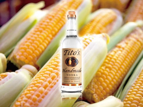 Tito's Handmade Vodka bottle surrounded by freshly harvested yellow corn