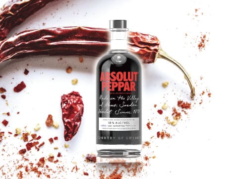 Absolut Peppar pepper-flavored vodka bottle surrounded by dried red chili peppers and chili flakes