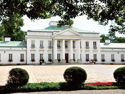 White neoclassical Belweder Palace with green roof and manicured garden in Warsaw, Poland