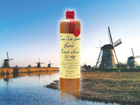 A bottle of aged Dutch genever displayed against a backdrop of traditional windmills and a canal