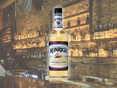 A bottle of Ronrico 151 gold rum on a bar counter, with shelves of spirit bottles in the background