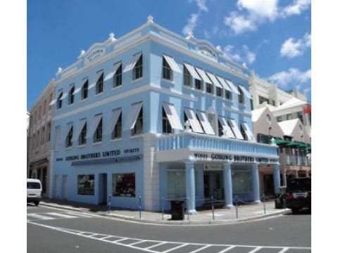 The pale blue historic Gosling Brothers United building on a street corner in Bermuda