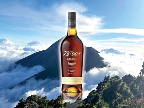 A bottle of Ron Zacapa 23 rum standing above cloud-covered mountain peaks in Guatemala's highlands