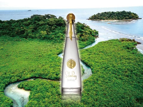 A tall SelvaRey white rum bottle towering over an aerial view of Panama's lush jungle coastline and small islands