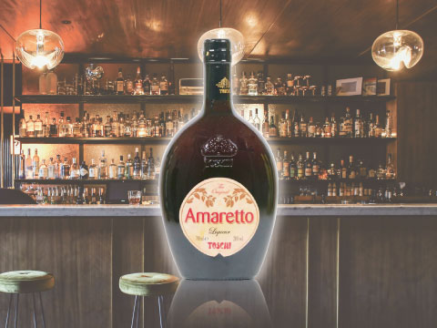 A bottle of Toschi Amaretto liqueur displayed on a bar counter, with shelves of bottles in the background
