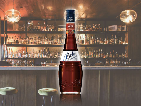 A bottle of Bols Amaretto liqueur displayed on a bar counter, with shelves of bottles in the background