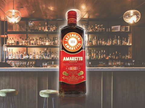 A bottle of Lazzaroni Amaretto liqueur displayed on a bar counter, with shelves of bottles in the background