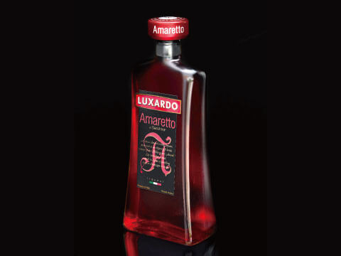 A bottle of Luxardo Amaretto liqueur with a red cap and label, photographed against a dark background