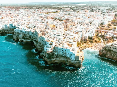 Aerial view of a white coastal town perched on cliffs above the turquoise waters of the Adriatic Sea in Italy