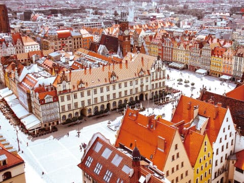 Aerial view of colorful historic buildings surrounding the market square in Wrocław, Poland, dusted with snow