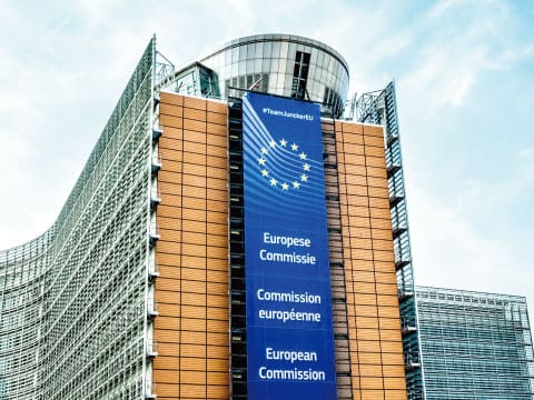 The European Commission building in Brussels, displaying banners in Dutch, French, and English on its facade