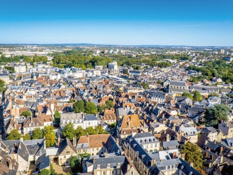 Aerial view of Bourges, France, showing dense historic rooftops and buildings under a clear blue sky