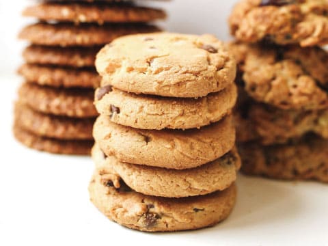 Stacks of chocolate chip cookies and oatmeal cookies arranged on a white surface