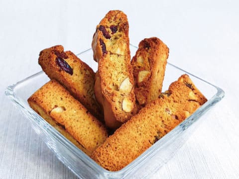 A glass bowl filled with biscotti cookies studded with almonds and dried cranberries