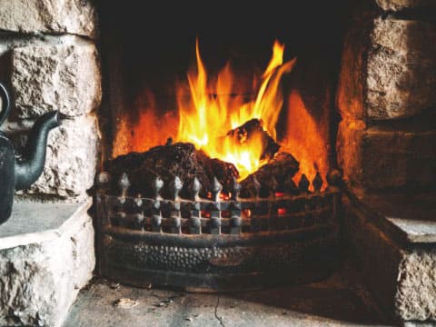 Blocks of peat burning in a stone fireplace, the traditional fuel whose smoke gives whiskey its peaty, smoky aroma