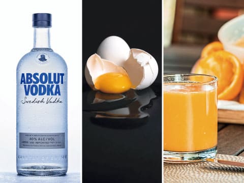 Creamy Driver ingredients: a bottle of Absolut Vodka, a cracked egg with its yolk, and a glass of fresh orange juice