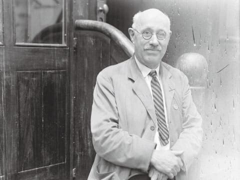 Black-and-white photo of William E. "Pussyfoot" Johnson, the American prohibition campaigner, wearing round glasses and a striped tie beside a wooden door