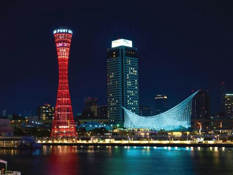 Night view of Kobe Port, Japan, with the red Kobe Port Tower and the illuminated Maritime Museum reflected on the harbor