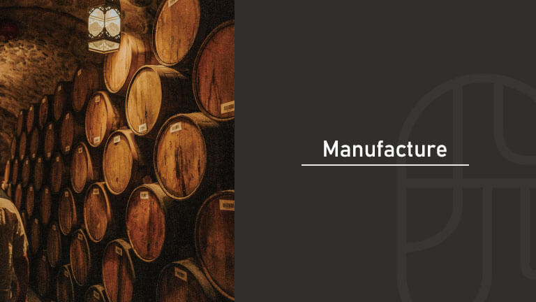 Wooden aging barrels stacked in a dimly lit cellar, next to text reading "Manufacture," representing the fermentation, distillation, and compounding methods used to produce alcohol