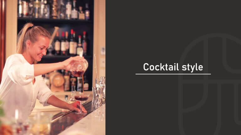 A female bartender pouring a cocktail from a mixing glass into a coupe glass at a bar, next to text reading "Cocktail style"
