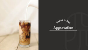 Milk being poured into a glass of layered dark Aggravation cocktail with swirling patterns, on a wooden table