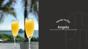 Two glasses of orange-colored Angelo cocktail in champagne flutes on a table, with palm trees and ocean in the background