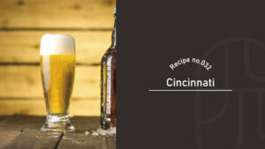Recipe no.032 title card for the Cincinnati cocktail, featuring a foam-topped beer glass beside a dark glass bottle on a wooden bar counter