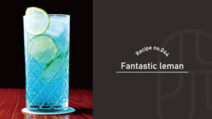 A blue Fantastic Leman cocktail garnished with two lime wheels, served in a textured glass on a wooden table