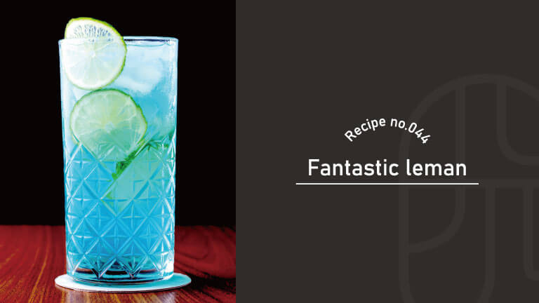 A blue Fantastic Leman cocktail garnished with two lime wheels, served in a textured glass on a wooden table