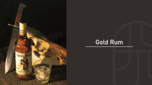 A bottle of Captain Morgan Original Spiced Gold rum beside a machete and animal skull on a woven mat