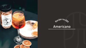 A red Americano cocktail with an orange slice garnish in a wine glass, served on a wooden board with dried citrus wheels