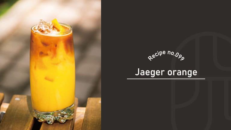 A tall glass of orange Jaeger Orange cocktail with a dark liqueur layer floating on top, garnished with an orange slice and ice, on a wooden outdoor table, beside a "Recipe no.099 Jaeger orange" title card