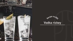 Two clear Vodka Rickey cocktails in tall glasses garnished with lime wedges, set on a bar counter