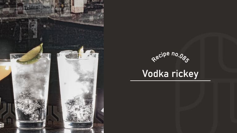 Two clear Vodka Rickey cocktails in tall glasses garnished with lime wedges, set on a bar counter
