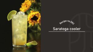 A pale yellow Saratoga Cooler cocktail served over ice in a tall glass, garnished with a lime wheel and lime wedge