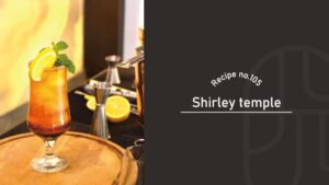 A tall glass of layered orange-to-red Shirley Temple mocktail garnished with mint and an orange wheel, on a wooden bar tray, beside a "Recipe no.105 Shirley temple" title card
