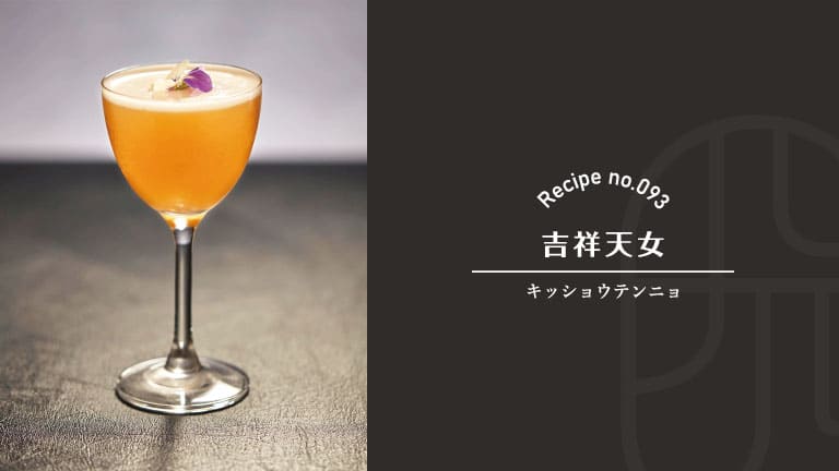 A stemmed glass of amber-orange Kisshoten Nyo cocktail with soft white foam, garnished with a single purple flower petal, set on a dark stone surface, beside a "Recipe no.093 吉祥天女 Kisshoten Nyo" title card