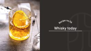 Whisky Today cocktail in a cut-crystal rocks glass garnished with an orange slice on a cocktail pick, with ice cubes and bar picks on a stone counter