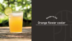 Orange Flower Cooler cocktail in a tall glass, a pale golden-orange drink over ice with a lime wheel on the rim, on a rustic wooden table outdoors with green trees behind — Recipe no.145