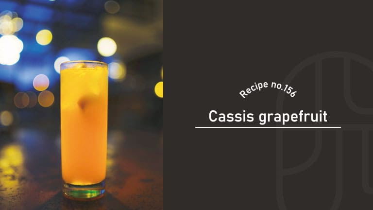 Cassis Grapefruit cocktail, a bright citrus highball over ice in a tall glass on a bar counter, with glowing bokeh lights in the background, Recipe No.156