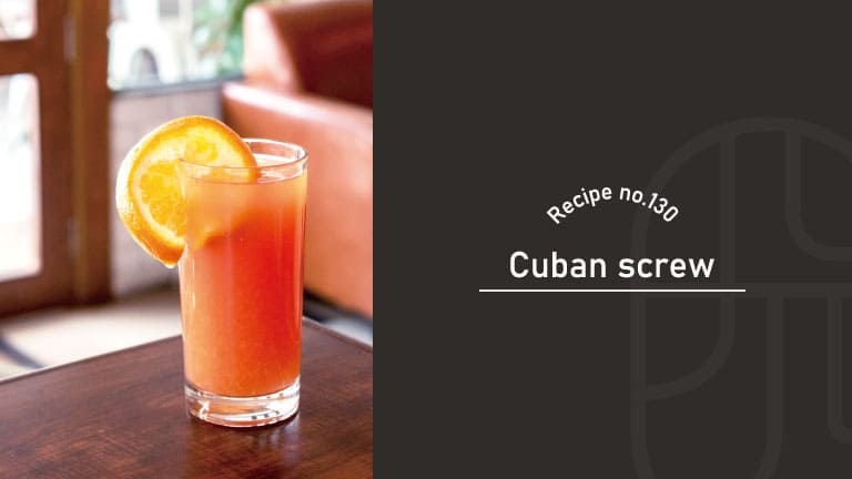 Cuban Screw cocktail with a bright orange color in a tall glass, garnished with an orange slice on a wooden table in a cozy café