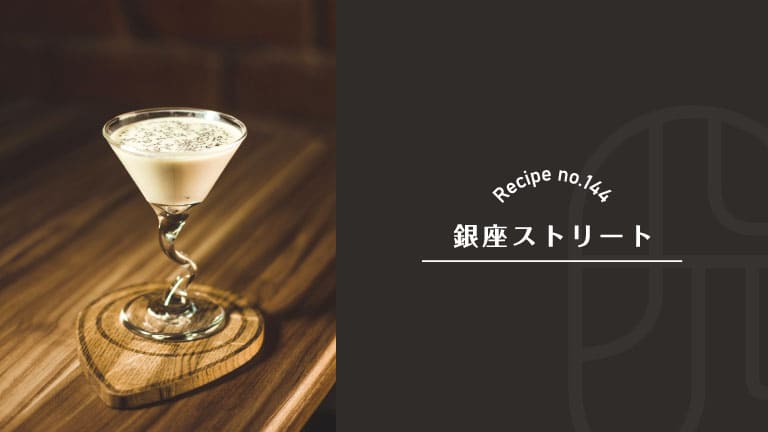 Ginza Street cocktail, a creamy white drink dusted with a fine topping, served in a cocktail glass with a twisted stem on a heart-shaped wooden coaster — Recipe no.144